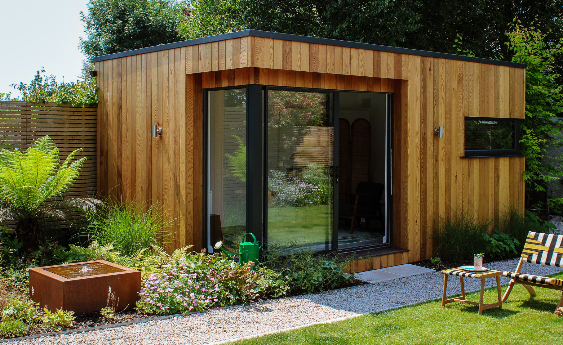 Corten steel water feature beside a cedar-clad garden room